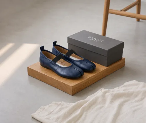 A pair of premium DayLife Leather navy blue tabi-toe Mary Jane flat shoes with black elastic straps, displayed on a wooden block next to a branded grey shoe box at DayLifeLeather.com.
