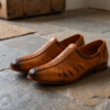 Side view of a pair of men's tan genuine leather mojari style loafers, featuring laser-cut breathable design and a burnished dual-tone finish.