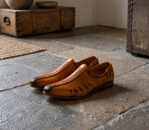 Side view of a pair of men's tan genuine leather mojari style loafers, featuring laser-cut breathable design and a burnished dual-tone finish.