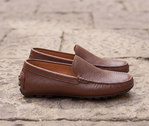 Close-up shot of a man wearing premium brown textured leather loafers, comfortable slip-on leather shoes for men.