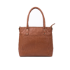 Side profile view of a DayLife Leather women's shoulder bag in a peach-pink hue, resting on a dark wood table with blurred background books.