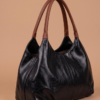 Daylife Leather Black and Brown Hobo Bag Daylife Leather dual-tone hobo shoulder bag featuring a glossy black leather body and brown handles against a beige background.