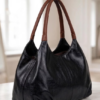 Screenshot 2026-07-26 230553 Daylife Leather dual-tone hobo shoulder bag featuring a glossy black leather body and brown handles against a beige background.