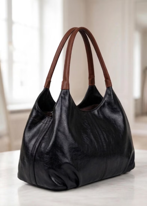 Screenshot 2026-07-26 230553 Daylife Leather dual-tone hobo shoulder bag featuring a glossy black leather body and brown handles against a beige background.