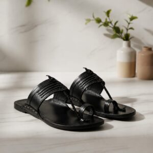 Handcrafted black leather toe ring sandals with braided strap detail on a marble surface