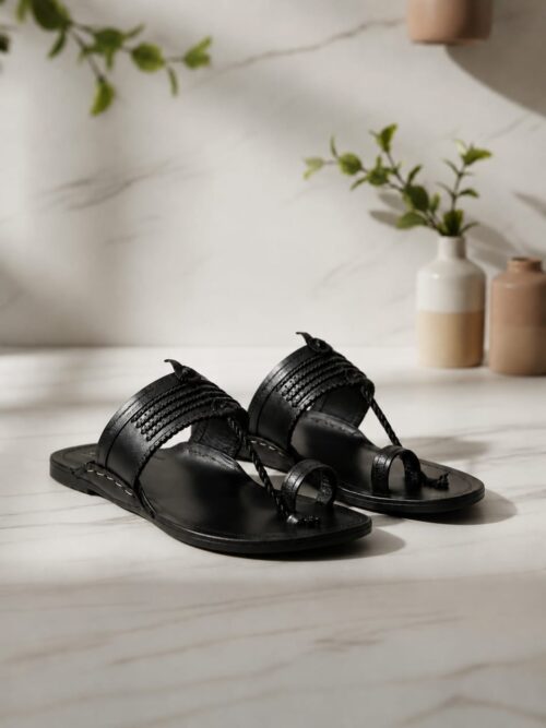 Handcrafted black leather toe ring sandals with braided strap detail on a marble surface