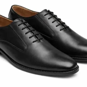 Side profile view of a single black leather Oxford shoe against a white background, showing the arch and heel height.
