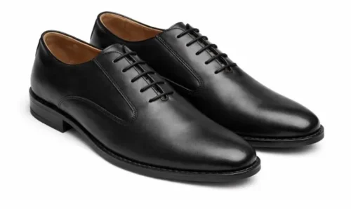 Side profile view of a single black leather Oxford shoe against a white background, showing the arch and heel height.