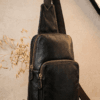 Handcrafted black textured leather sling bag with antique brass zippers and adjustable crossbody strap