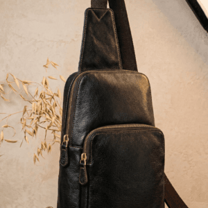 Handcrafted black textured leather sling bag with antique brass zippers and adjustable crossbody strap