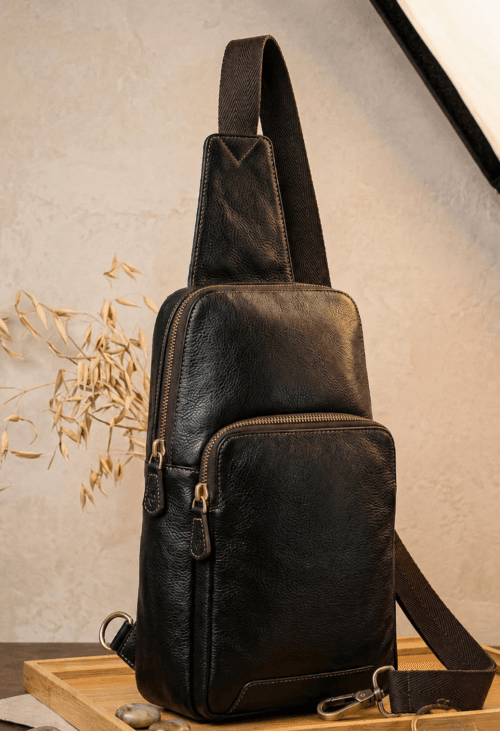 Handcrafted black textured leather sling bag with antique brass zippers and adjustable crossbody strap