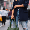 Woman holding green leather tote bag with a smile