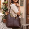 Woman carrying brown leather hobo bag on her shoulder outdoors