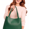 Woman holding green leather tote bag with a smile