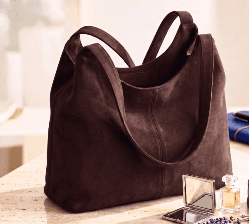Brown leather hobo bag styled with perfume and mirror on vanity