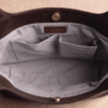 Brown leather hobo bag styled with perfume and mirror on vanity