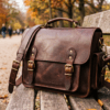 DayLife Leather vintage brown full-grain leather messenger bag resting on a wooden bench in a park.
