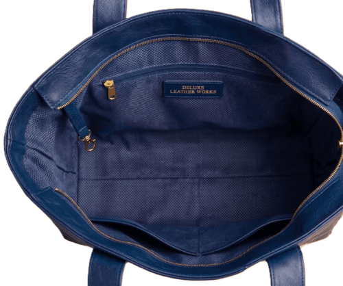 Open top view of navy blue leather bag showing spacious interior lining, zip compartment, and pockets Open top view of navy blue leather bag showing spacious interior lining, zip compartment, and pockets