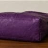 Deep purple genuine leather hobo bag with gold buckle strap on wooden surface