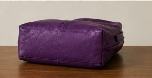 Deep purple genuine leather hobo bag with gold buckle strap on wooden surface