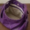 Deep purple genuine leather hobo bag with gold buckle strap on wooden surface