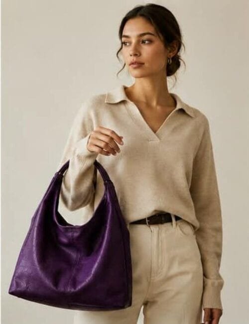 Deep purple genuine leather hobo bag with gold buckle strap on wooden surface