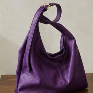 purple-leather-hobo-bag-gold-buckle-women Deep purple genuine leather hobo bag with gold buckle strap on wooden surface