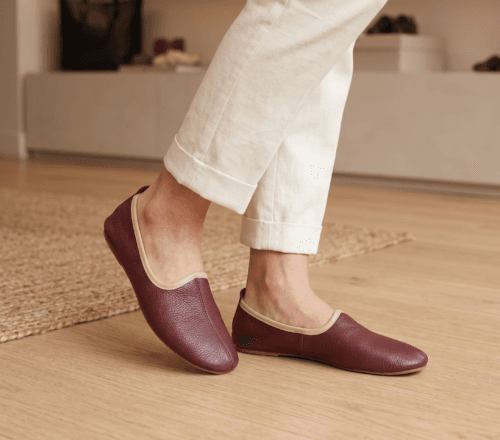 Men's maroon leather juti slip-on shoes with beige piping and suede-lined interior, side view