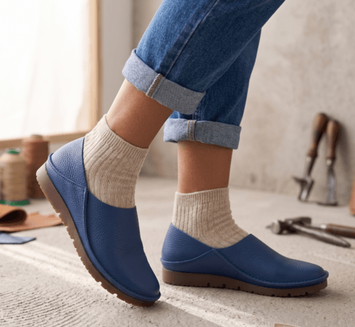 Men's navy blue pebbled leather slip-on shoes with beige ribbed sock-style collar and brown rubber sole