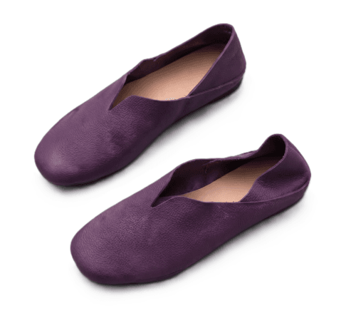 A product photography composite image showing a pair of handcrafted deep purple, pebbled leather flat shoes arranged in three views on a light gray background. The left panel shows the top-down (upper) view, the center panel shows the side profile, and the right panel shows the rear (back) view.