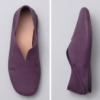 A product photography composite image showing a pair of handcrafted deep purple, pebbled leather flat shoes arranged in three views on a light gray background. The left panel shows the top-down (upper) view, the center panel shows the side profile, and the right panel shows the rear (back) view.
