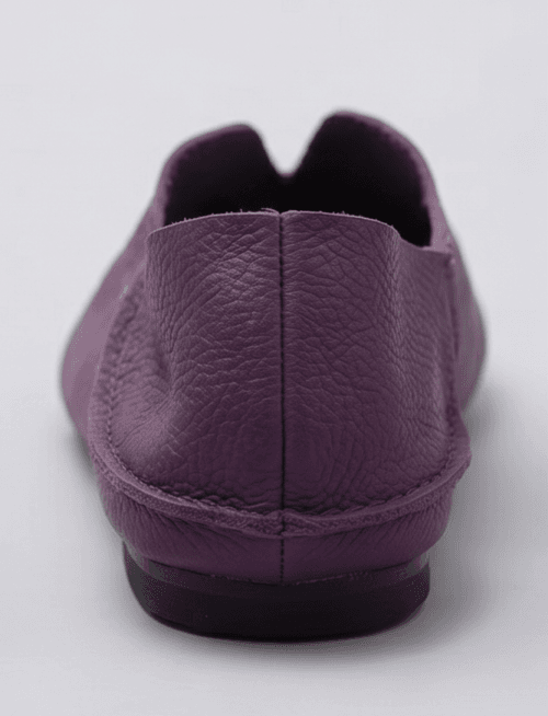 A product photography composite image showing a pair of handcrafted deep purple, pebbled leather flat shoes arranged in three views on a light gray background. The left panel shows the top-down (upper) view, the center panel shows the side profile, and the right panel shows the rear (back) view.