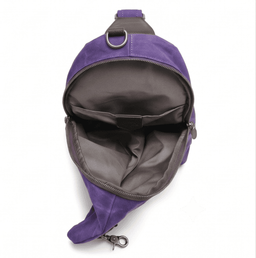 Male model wearing a vintage purple waxed canvas crossbody sling backpack by Daylife Leather on an urban cobblestone street, featuring product close-up and open interior view.