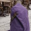 Male model wearing a vintage purple waxed canvas crossbody sling backpack by Daylife Leather on an urban cobblestone street, featuring product close-up and open interior view.